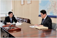 福井県安全環境部清水部長(左)に報告する原子力事業本部長代理の水田(右)