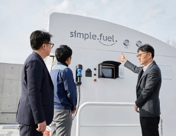 水素製造装置の前でふくい水素エネルギー協議会の海道雅俊さん（写真右）から説明を受ける