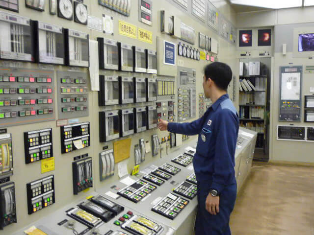 モニターや計器類で発電設備の状態を確認し機器を操作する作業員